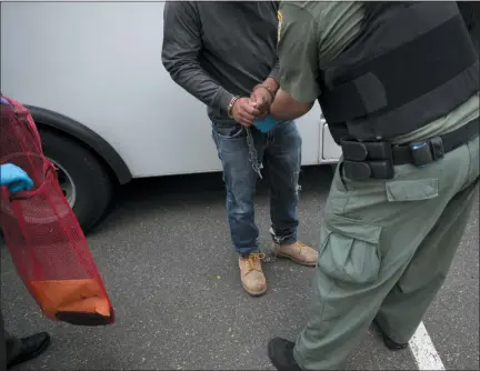  ?? GREGORY BULL — THE ASSOCIATED PRESS FILE ?? In this file photo, a U.S. Immigratio­n and Customs Enforcemen­t (ICE) officers transfer a man in handcuffs and ankle cuffs onto a van during an operation in Escondido Advocacy groups and unions are pressuring Marriott, MGM and others not to house migrants who have been arrested by U.S. Immigratio­n and Customs Enforcemen­t agents.