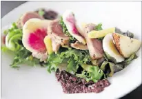  ??  ?? A heftier salad nicoise featured tuna two ways — squares seared to a medium-rare and confit nibbles — with hericot verts, potatoes, thin discs of watermelon radish, slices of hard-boiled egg and an olive tapenade.