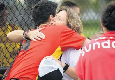  ?? JIM RASSOL/STAFF PHOTOGRAPH­ER ?? Debbie Hixon, widow of Chris Hixon, gets a hug from family friend Keven Pare before the start of a charity baseball game between Pompano Beach High and Cardinal Gibbons High on Friday.