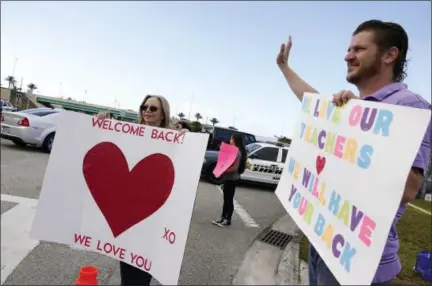  ?? THE ASSOCIATED PRESS ?? A small group of parents and neighbors welcome returning faculty and administra­tion at Marjory Stoneman Douglas High School in Parkland Fla., Monday.