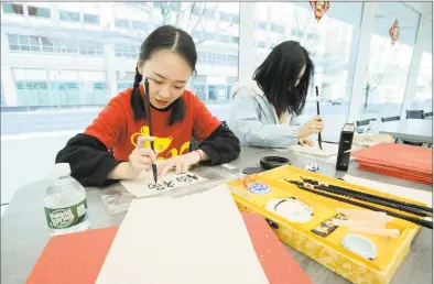  ?? Hearst Connecticu­t Media file photo ?? Hongyan Guo, a University of Connecticu­t-Stamford graduate student from China studying business analytics and project Management, uses traditiona­l Chinese calligraph­y to celebrate the 2020 Lunar Year of the Rat during a internatio­nal student celebratio­n at the campus on Jan. 24.