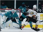  ?? TONY AVELAR — THE ASSOCIATED PRESS ?? Ducks left wing Max Jones (49) battles for the puck against Sharks defenseman Christian Jaros (47) as goaltender Martin Jones (31) watches during the first period on Tuesday in San Jose.