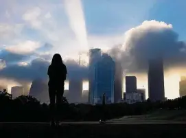  ?? Elizabeth Conley/Staff photograph­er ?? A woman watches an early morning fog rolls out of downtown Houston from Eleanor Tinsley Park. The city could need a fifth area code by late 2025.