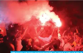  ?? — AFP ?? TUNIS: Supporters of the Tunisian Islamist-inspired Ennahdha party celebrate in reaction to the first exit polls in front of the party’s office in the capital Tunis.