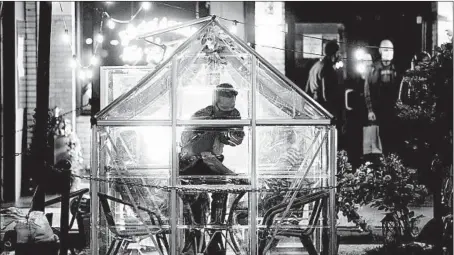  ?? ARMANDO L. SANCHEZ/CHICAGO TRIBUNE ?? An employee cleans a dining table inside a small greenhouse at the The Darling on Oct. 22 in Chicago’sWest Loop.