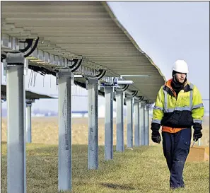  ?? AP/JEFF MOREHEAD ?? A worker walks beneath solar panels being installed at Madison-Grant High School near Fairmount, Ind., on Dec. 21.