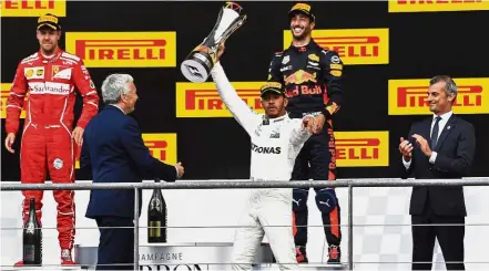  ??  ?? Historic: Mercedes driver Lewis Hamilton of Britain (centre) raising his trophy on the podium after winning the Belgian Grand Prix in Spa-Francorcha­mps, Belgium yesterday. Ferrari driver Sebastian Vettel of Germany (left) was placed second and Red Bull...