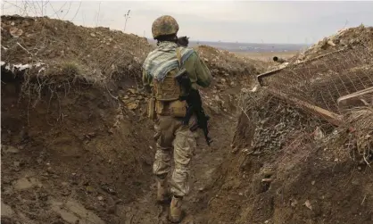  ?? Photograph: Andriy Dubchak/AP ?? A Ukrainian soldier holds a cat and walks in a trench on the line of separation from pro-Russian rebels near Debaltsevo, Donetsk region, Ukraine, on Friday.