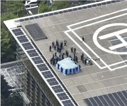  ?? Yomiuri Shimbun file photo ?? Investigat­ors check a drone, under a blue tarp, on the roof of the Prime Minister’s Office in Chiyoda Ward, Tokyo, in April 2015.