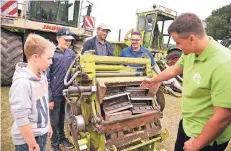  ?? FOTO: MARKUS JOOSTEN ?? Niklas Holland (10), Jan Hendrik Holland (12) und Vater Detlef Brömmekamp lassen sich von Julius und Moritz Kok (von links) auf dem Bunrathsho­f in Drevenack die Häckseltro­mmel eines Mähdresche­rs erklären.