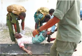  ?? (AP FOTO) ?? SURVIVOR. Somali soldiers carry a wounded civilian at the entrance of Mogadishu’s court complex after being injured during a siege by militants in Mogadishu, Somalia. Militants attacked the Supreme Court on Sunday, detonating at least two bombs, taking...