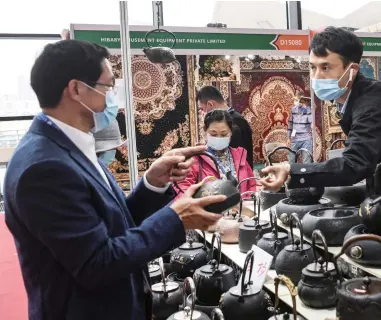  ??  ?? On November 27, 2020, a consumer (first L) selects tea pots at BRI internatio­nal exhibition area of the Internatio­nal Convention and Exhibition Center of Nanning, Guangxi.