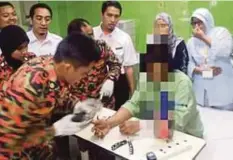  ??  ?? PASUKAN bomba melakukan kerja menanggalk­an cincin yang tersekat.