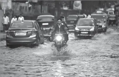  ?? SHAILESH ANDRADE / REUTERS ?? People commute along a water-logged street after rains in Mumbai, India, on Wednesday. The monsoon caused disruption to air and road transport and forced the closures of schools and colleges.