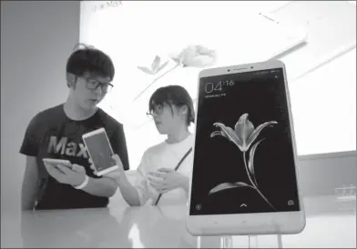  ?? REUTERS ?? A consumer (right) receives informatio­n about Xiaomi’s new smartphone Mi Max from a staff member at the flagship product’s launch in Beijing.