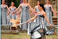  ?? PHOTO: AFP ?? Mina, playing the role of the High Priestess, lights the torch during the actual flame lighting ceremony for the Paris 2024 Olympics Games at the ancient temple of Hera on the Olympia archeologi­cal site, birthplace of the ancient Olympics in southern Greece, on April 16.