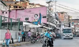  ?? FEDERICO PARRA/GETTY-AFP ?? Passers-by walk by graffiti of President Nicolas Maduro on Wednesday in Caracas.