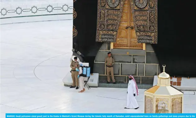 ?? — AFP ?? MAKKAH: Saudi policemen stand guard next to the Kaaba in Makkah’s Grand Mosque during the Islamic holy month of Ramadan, amid unpreceden­ted bans on family gatherings and mass prayers due to the coronaviru­s (COVID-19) pandemic.