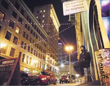  ?? Rick Loomis Los Angeles Times ?? A SECURITY GUARD checks the IDs of patrons entering Bar 107 in downtown L.A., which is facing the loss of its lease. The bar’s owner has vowed not to leave without a fight, and has hit a sweet spot on social media.