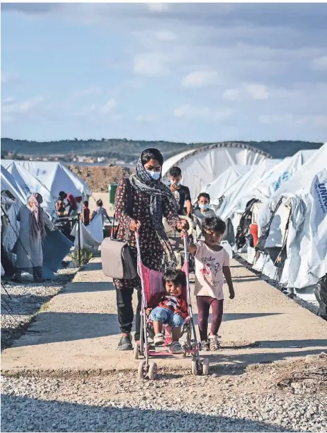  ?? FOTO: PANAGIOTIS BALASKAS/DPA ?? Migranten gehen Ende Oktober nach starken Regenfälle­n durch das Flüchtling­slager Kara Tepe.