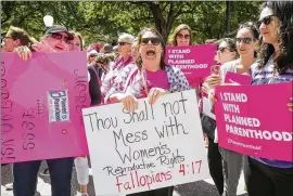  ?? JAY JANNER / AMERICAN-STATESMAN ?? Linda Overfield (center), of New Braunfels, holds a sign at a rally for Planned Parenthood at the Capitol on April 5.