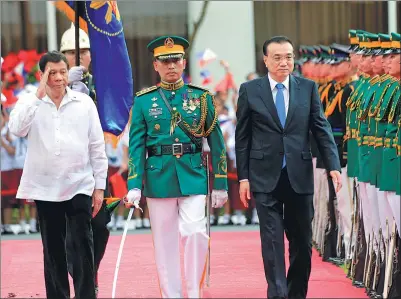  ?? ROMEO RANOCO / REUTERS ?? Premier Li Keqiang reviews an honor guard with a saluting Philippine President Rodrigo Duterte upon Li’s arrival for an official visit at the Malacanang presidenti­al palace in Manila on Wednesday.