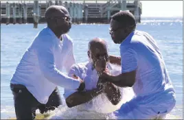  ??  ?? Tata Illunga rises out of the Chesapeake Bay immediatel­y after being baptized at the Community Holy Baptism event held in North Beach on Aug. 13. Pastors Tony Massamba and Assani Saidi of the Revelation Church in Silver Spring officiated over Illunga’s...