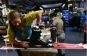  ?? ?? Aunika Skogen fits boots onto skis for a customer at Larsons’s Ski & Sport on Nov. 10. Customers who learned to ski 30 years ago now bring their kids in for fittings.