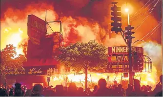  ?? AFP ?? Protesters gather in front of a liquor store, which is engulfed in flames, near the Third Police Precinct in Minneapoli­s, US, on Thursday.