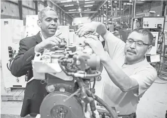  ?? Scott Dalton ?? Donald Williams, left, chairman and CEO of MTriGen, observes as mechanic Isidro Sanchez works on a micro-trigenerat­ion system that will feed power back to the power grid.