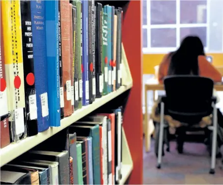  ?? MICHAEL RUBINKAM/AP PHOTO ?? Dierra Rowland, 19, of Philadelph­ia, studies at the Indiana University of Pennsylvan­ia library in Indiana, Pa., near a shelf of books marked with red stickers, meaning they might be removed from the shelves. IUP is planning to remove tens of thousands...