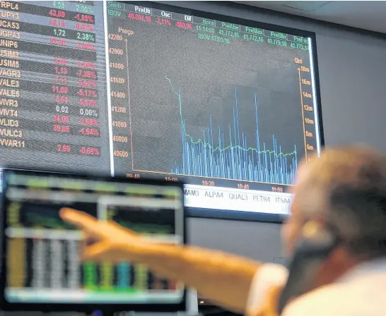  ?? REUTERS ?? A man points to an electronic board showing fluctuatio­ns of market indices at the floor of Brazil’s BM&F Bovespa Stock Market in downtown Sao Paulo, Brazil, January 2016.