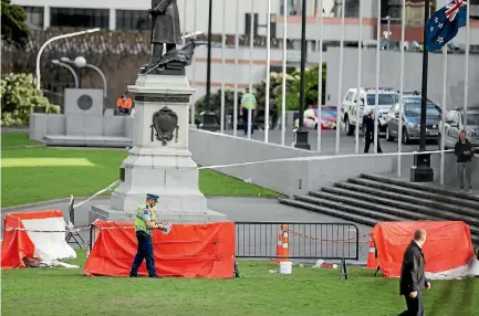  ?? PHOTO: MAARTEN HOLL/STUFF ?? A police officer cordons off a patch of burnt grass outside Parliament in Wellington, where a man reportedly set himself on fire yesterday.