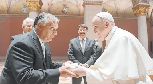  ?? The Associated Press ?? Pope Francis exchanges gifts with Hungarian Prime Minister Viktor Orban at Budapest’s Museum of Fine Arts on Sunday.