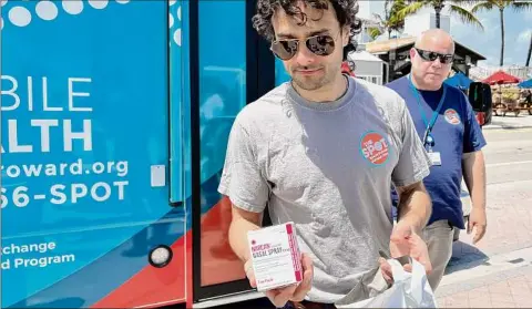  ?? Freida Frisaro / Associated Press ?? Huston Ochoa, a clinical counselor for The Spot, hands out samples of Narcan, which can reduce opioid overdoses, to spring breakers on Fort Lauderdale Beach, Fla. Community activists are warning spring breakers of a surge in recreation­al drugs being laced with the dangerous opioid fentanyl, and offered them an antidote for overdoses.