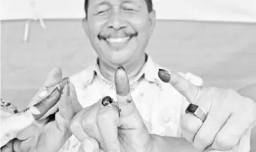  ??  ?? Indonesian men show their inked fingers after casting their ballots during regional elections in Tangerang, Banten. — AFP photo