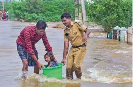  ?? — PTI ?? A child sitting in a bucket being evacuated by a man and a policeman from a flooded area of Verma Nagar due to the overflowin­g Ariyar river following heavy rains in Trichy district on Tuesday.