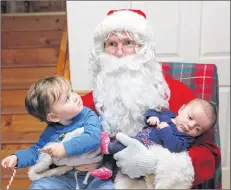  ?? KARLA KELLY ?? Bennett Sabine eyes Santa warily as his baby cousin Brynlee Mellor-Amero does not seem the least bothered by who is holding her.