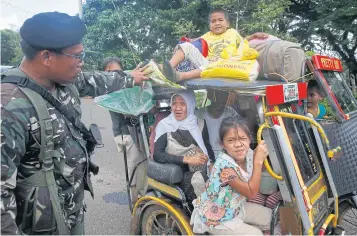  ?? AP ?? Residents fleeing the besieged city of Marawi are questioned at a checkpoint by government soldiers yesterday.