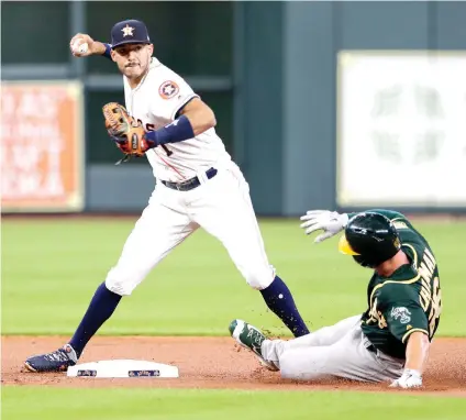  ?? Michael Wyke/Associated Press ?? ■ Houston Astros shortstop Carlos Correa (1) turns the double play at second base as Oakland Athletics' Matt Chapman (26) slides in during the first inning of a baseball game Wednesday in Houston.