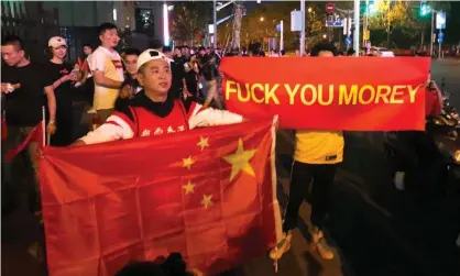  ?? Photograph: AFP/Getty Images ?? A file photo taken in Shanghai in October 2019 shows people holding the Chinese flag and a protest banner in reference to a controvers­ial tweet by then-Rockets general manager Daryl Morey.