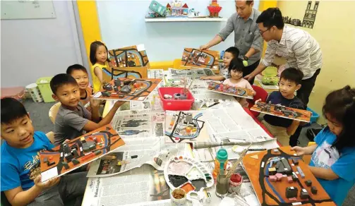  ?? GUSLAN GUMILANG/JAWA POS ?? SUDAH JADI: Anak-anak memperliha­tkan maket-maket buatan mereka. Melalui pembuatan maket, mereka belajar tentang tipologi bangunan dan tata kota.