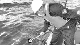  ?? Handout / Philippine Coast Guard (PCG) / AFP ?? In this handout photo received from the Philippine Coast Guard and taken on March 2, 2023, a coast guard personnel collects water sample from of an oil spill in the waters off Naujan, Oriental Mindoro.