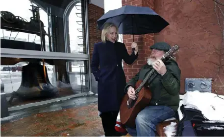  ?? AP ?? SINGIN’ IN THE RAIN: U.S. Sen. Kirsten Gillibrand (D-N.Y.) sings a Cat Stevens song with street musician Kevin Clark while campaign for president in Concord, N.H., Friday.