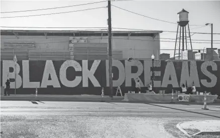  ?? PHOTOS BY GAELEN MORSE/COLUMBUS DISPATCH ?? Artists paint a large mural along Fifth Avenue in the Milo-grogan neighborho­od. It is the first in a series of six that will be created throughout the city as part of the “Delivering Black Dreams” campaign.