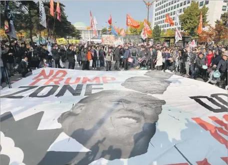  ?? Ahn Young-joon Associated Press ?? PROTESTERS in Seoul, South Korea’s capital, hurl salt at a banner of President Trump last week as they demonstrat­e against his visit.