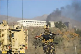  ?? Wakil Kohsar / AFP / Getty Images ?? An Afghan officer patrols as smoke billows from the Interconti­nental Hotel in Kabul during a gunbattle between militants and state security forces. The Taliban claimed responsibi­lity.