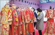  ?? DING GENHOU / FOR CHINA DAILY ?? Visitors select wedding costumes at an exposition in Hohhot, Inner Mongolia autonomous region.