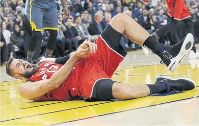  ?? JEFF CHIU THE ASSOCIATED PRESS ?? Toronto Raptors centre Jonas Valanciuna­s reacts after injuring his hand during the first half of a game against the Golden State Warriors in Oakland last Wednesday. He won’t be playing for months, one of the team’s first long-term injuries this season.