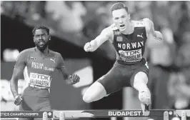  ?? PETR DAVID JOSEK AP ?? Norway’s Karsten Warholm clears the final hurdle ahead of Kyron McMaster, of the British Virgin Islands, to win the gold medal in the 400-meter hurdles.